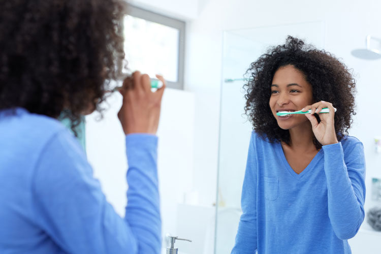 Woman Brushing Teeth in Mirror