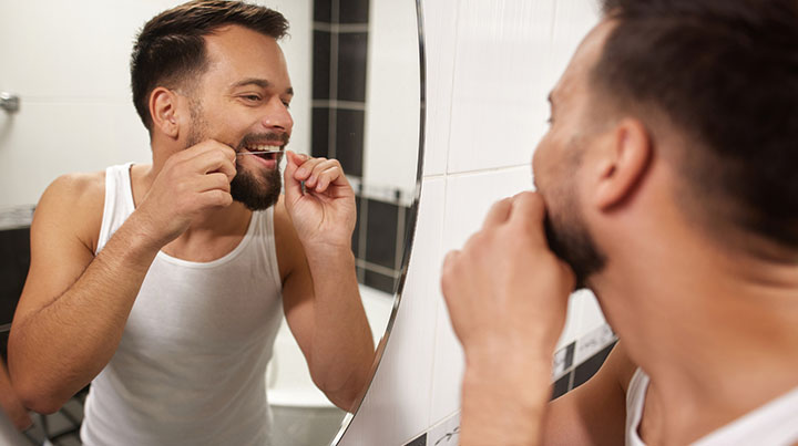 male flossing teeth mirror